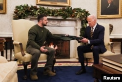 FILE - Ukraine's President Volodymyr Zelenskyy present a soldier's medal to President Joe Biden in the Oval Office at the White House in Washington, Dec. 21, 2022.