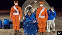 In this photo released by Xinhua News Agency, astronaut Chen Dong waves as he sits outside the re-entry capsule of the Shenzhou-14 manned space mission after it lands successfully at the Dongfeng landing site. 