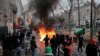 Demonstrators stand next to a burning barricade during a protest against the recent shooting at the Kurdish culture center in Paris, Saturday, Dec. 24, 2022. 