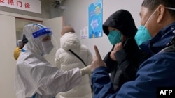 A health worker, left, talks to people at a fever clinic at the First Affiliated Hospital of Chongqing Medical University amid the COVID-19 pandemic in China's southwestern city of Chongqing on Dec. 22, 2022.