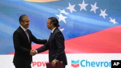 El ministro de Petróleo de Venezuela, Tareck El Aissami (izq) estrecha la mano del presidente de Chevron en Venezuela, Javier La Rosa, el 2 de diciembre de 2022.