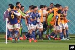 FILE - Japan players celebrate after Takuma Asano scored his side's second goal during the World Cup Group E soccer match between Germany and Japan, at the Khalifa International Stadium in Doha, Qatar, Nov. 23, 2022.