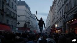 A member of the Kurdish community stands on the top of a car during clashes with police officers near the crime scene where a shooting took place in Paris, Dec. 23, 2022.