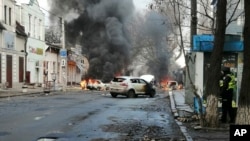 FILE - Cars burn and smoke raises after a deadly Russian rocket attack hit the city center in Kherson, Ukraine, Dec. 24, 2022. 