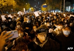 FILE - Protesters march along a street during a rally for the victims of a deadly fire, as well as a protest against China's harsh COVID-19 restrictions, in Beijing on Nov. 28, 2022.