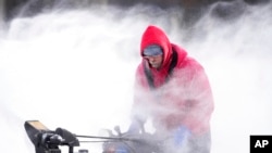 Mark Sorter clears snow from a downtown ice skating rink, Dec. 23, 2022, in Des Moines, Iowa.