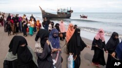 FILE - Ethnic Rohingya refugees walk to a temporary shelter after they landed on their wooden boat in North Aceh, Indonesia, Nov. 16, 2022.