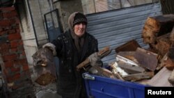 A woman loads firewood in the formerly Russian occupied city of Lyman, Donetsk region of Ukraine, Dec. 11, 2022. 