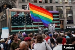 FILE - A rainbow flag flies as people protest U.S. President Donald Trump's announcement that he plans to reinstate a ban on transgender individuals from serving in any capacity in the U.S. military, in Times Square, in New York City, New York, July 26, 2017.