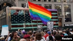 A rainbow flag flies as people protest U.S. President Donald Trump's announcement that he plans to reinstate a ban on transgender individuals from serving in any capacity in the U.S. military, in Times Square, in New York City, New York, July 26, 2017. 