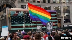 FILE - A rainbow flag flies as people protest U.S. President Donald Trump's announcement that he plans to reinstate a ban on transgender individuals from serving in any capacity in the U.S. military, in Times Square, in New York City, New York, July 26, 2017. 