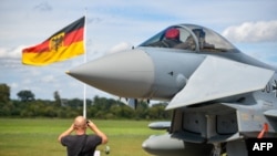 FILE - This file photo taken on Aug. 20, 2020 shows a man taking pictures of an Eurofighter jet of the German Air Force on the tarmac of the German Armed Forces (Bundeswehr) airbase in Noervenich, western Germany. 