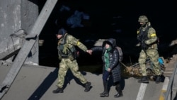 Yon manm fos Ikrenyen yo ede yon dam travese rivye Irpin nan pandan evakyasyon vil Irpin, bo kote yon pon ki detwi pandan envazyon La Risi fe nan Ikren, Dimanch 13 Mas, 2022. 