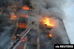 Tim penyelamat bekerja di sebelah bangunan tempat tinggal yang rusak akibat penembakan, saat serangan Rusia di Ukraina berlanjut, di Kyiv, Ukraina. (Foto: via REUTERS)