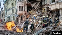 Rescuers work next to a building damaged by air strike, as Russia's attack on Ukraine continues, in central Kharkiv, Ukraine, March 14, 2022.