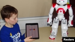 FILE - Daniel Connell uses a language-trainer robot, Elias, during his lesson at the school in Tampere, Finland, March 27, 2017. 