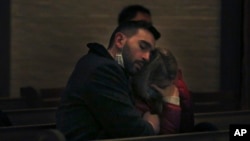 FILE - Michael Lo Piano, left, comforts Oksana Hryvinska, as they listen to Ukrainian folk songs during a benefit concert for Ukraine at St. Thomas More Catholic Chapel in New Haven, Conn., March 16, 2022.