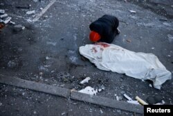 A man mourns next to the body of his mother, who was killed when an intercepted missile hit a residential building, during Russia's invasion of Ukraine, in Kyiv, March 17, 2022.