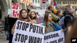 FILE - People hold banners and gather during a demonstration in Bern, Switzerland, Feb. 24 2022, following the Russian attack of Ukraine.