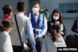 FILE - Afghan refugees who supported Canada’s mission in Afghanistan, are greeted before boarding a bus after arriving in Canada on a Canadian Forces CC-177 Globemaster transport plane at Toronto Pearson International Airport, Aug. 4, 2021.