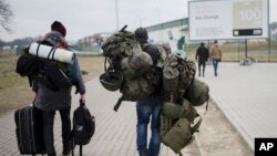 FILE - A man carries combat gear as he leaves Poland to fight in Ukraine, at the border crossing in Medyka, Poland, March 2, 2022.