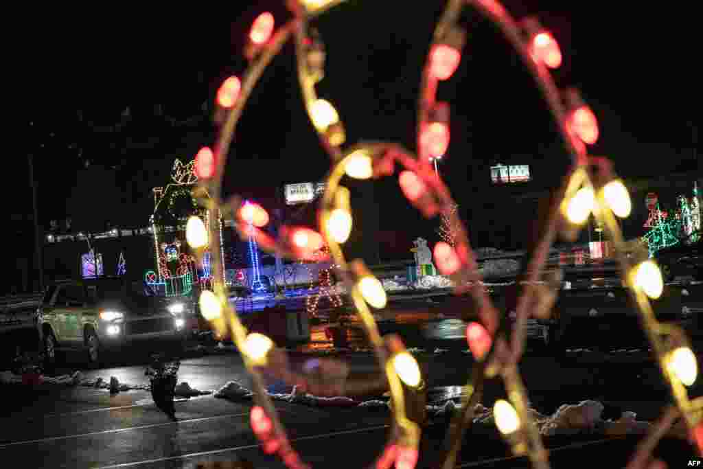 Al fondo los autos atraviesan el "Winter in Wilmington Light Show" en Wilmington, Delaware, el 18 de diciembre de 2020. [AFP]