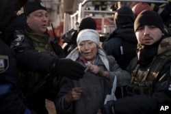 Policías ayudan a una anciana después de que los bomberos la rescataran del interior de su apartamento tras un bombardeo en Kiev, Ucrania, el martes 15 de marzo de 2022.