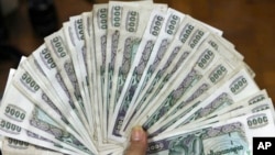 FILE - A woman shows Myanmar banknotes in Yangon, Myanmar, June 9, 2011. 