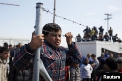 Migrants and refugees look on after minor clashes with Greek policemen occurred at a makeshift camp at the Greek-Macedonian border near the village of Idomeni, Greece, March 29, 2016.