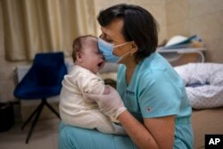 یکی از پرستاران با نوزادی بازی می‌کند