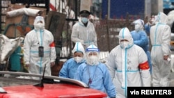 Medical workers in protective suits walk amid the snow as they enter a residential compound under lockdown to conduct testing, following a COVID-19 outbreak in Changchun, Jilin province, China March 14, 2022. (China Daily via Reuters)