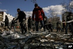 在基辅，当局说，一枚被乌克兰防空系统击落的俄罗斯导弹落在一处公寓楼群，人们在附近的医疗中西外清理破坏现场。(2022年3月17日)