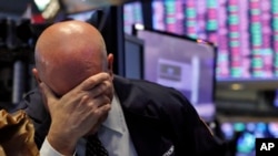 Un trader a la tête dans sa main sur le sol de la Bourse de New York, le jeudi 12 mars 2020. (AP Photo/Richard Drew)