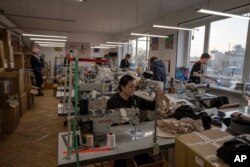 Displaced from Kyiv, Ukrainian hat makers for high-end designer brand Ruslan Baginskiy 'RB', work inside a classroom turned into a workshop for the company, in Lviv, western Ukraine, March 25, 2022.