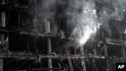 FILE - Firefighters try to extinguish a fire amid the destruction caused after shelling of a shopping center, in Kyiv, Ukraine, March 21, 2022.