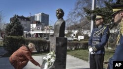 Žena polaže cveće na spomenik bivšoj američkoj državnoj sekretarki u Prištini(Foto: AP/Visar Kryeziu)