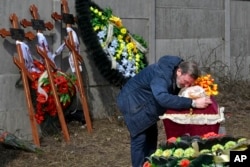 A relative mourns on the coffin holding the body of Mykola Goryainiv, 3, who died with his parents as they were driving a car trying to evacuate from a fighting zone in the Kharkiv region, during a funeral in Kramatorsk, Ukraine, March 30, 2022.