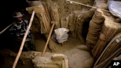 FILE - In Mes Aynak valley, southwest of Kabul, Afghanistan, an Afghan archeologist stands next to remains of Buddha statues discovered inside an ancient temple, Oct. 12, 2010.