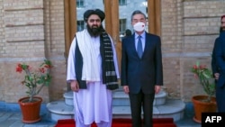 This handout photo released by the Taliban Foreign Ministry shows Taliban Foreign Minister Amir Khan Muttaqi, left, posing with China's Foreign Minister Wang Yi in Kabul on March 24, 2022.