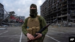 Ukrajinski vojnik stoji u centru Kijeva ispred tržnog centra uništenog u napada 21. marta 2022.