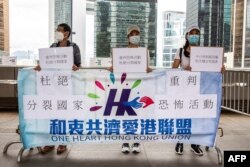 FILE - Pro-China demonstrators hold signs outside the High Court in Hong Kong on July 30, 2021, during sentencing for a man convicted of terrorism and inciting secession in the first trial conducted under a national security law imposed by China.