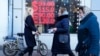 FILE - People walk past a currency exchange office screen displaying the exchange rates of the US dollar and euro to Russian rubles in Moscow, on Feb. 28, 2022. 
