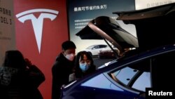 Pengunjung memeriksa kendaraan SUV Tesla Model Y buatan China di sebuah showroom di Beijing, China (foto: dok). Tesla masih mendominasi pasar mobil listrik global. 