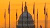 An early morning pedestrian is silhouetted against sunrise as he walks through the US flags on the National Mall and past the US Capitol Building in Washington, Nov. 7, 2022.