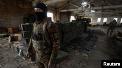 A Ukrainian soldier stands next to cases of ammunition abandoned by retreating Russian forces in the village of Blahodatne, in Ukraine's Kherson region, Nov. 11, 2022.