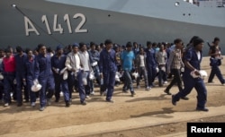 Migrants walk on the dock after disembarking from the German naval vessel Frankfurt Am Main in the Sicilian harbour of Augusta, Italy, April 12, 2016.