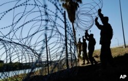 FILE - Members of the U.S. military install multiple tiers of concertina wire along the banks of the Rio Grande near the Juarez-Lincoln Bridge at the U.S.-Mexico border, Nov. 16, 2018, in Laredo, Texas.