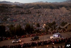 Pope Francis rides in his popemobile, right, as he greets people lining the road from El Alto to La Paz, upon his arrival to Bolivia, Wednesday, July 8, 2015.