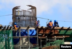 FILE - Workers balance on steel beams as they work on an expressway undergoing construction in Manila, Jan. 28, 2016.