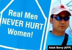 Seorang pria memegang plakat untuk membela perempuan. Komnas Perempuan mendorong orang untuk menghentikan kekerasan dalam rumah tangga (KDRT), masalah yang lazim dan sering diabaikan di masyarakat. (Foto: AFP/Adek Berry)